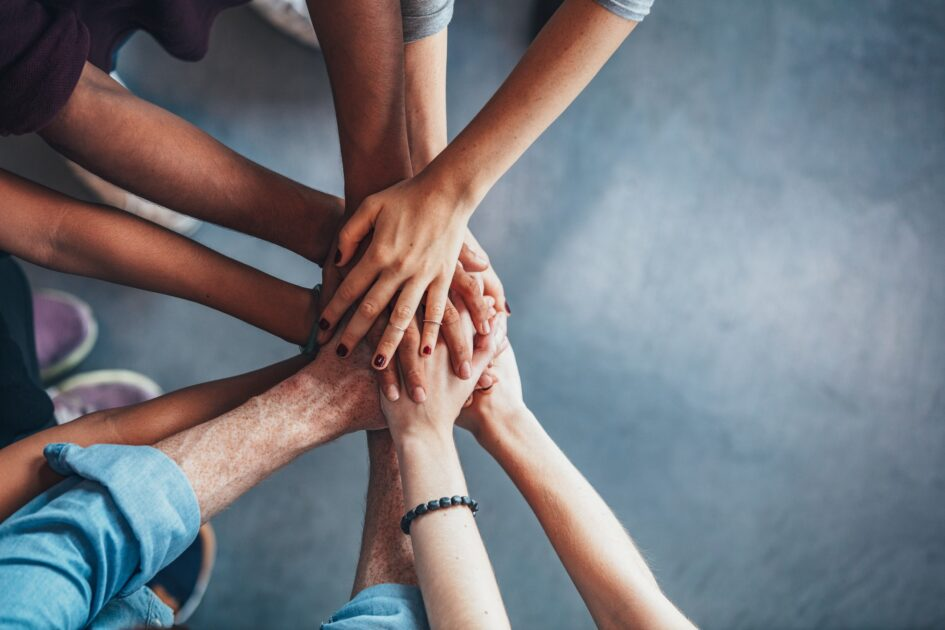 A team stacking their hands together in the middle of a circle.